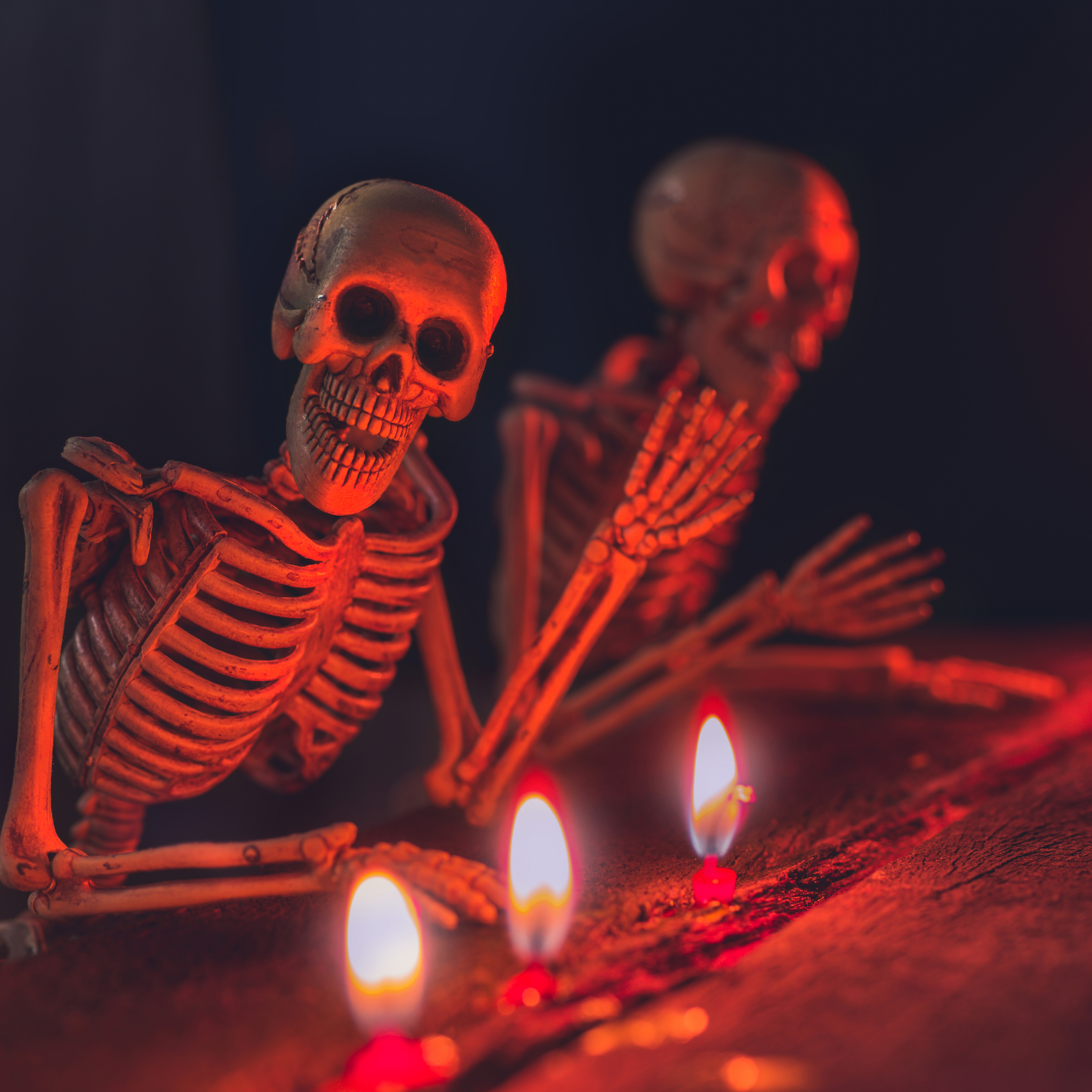 A skeleton lit by candles, smiling and waving at the viewer