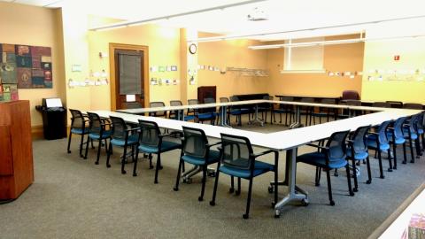 Photograph of the interior of the Central Library Community room showing modular tables and chairs arranged in a square pattern.