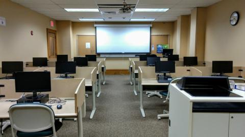 Photograph of the interior of the Central Library computer lab showing multiple computers facing a projector and podium at the front of the room.