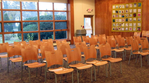 Photograph of the interior of the Mason Square branch library community room. Large window and several chairs.