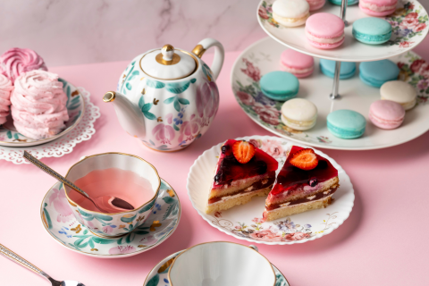 Photograph of a fancy pink tea party with pink tea and cheesecake and macarons