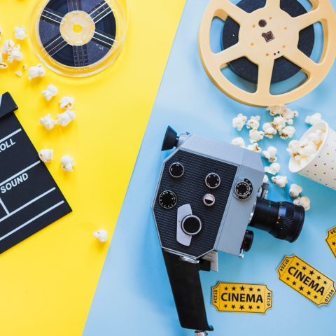 Clapperboard, rolls of film, video camera, movie tickets, and popcorn