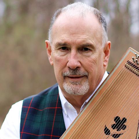 Jeff snow, a white man with gray goatee, in tartan, holding a mini harp.