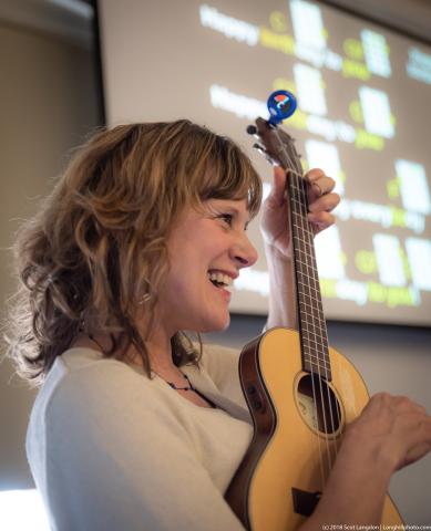 Picture of a woman laughing and holding a ukulele
