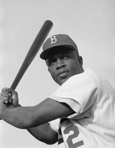 Black and white photo of Jackie Robinson preparing to swing a baseball bat