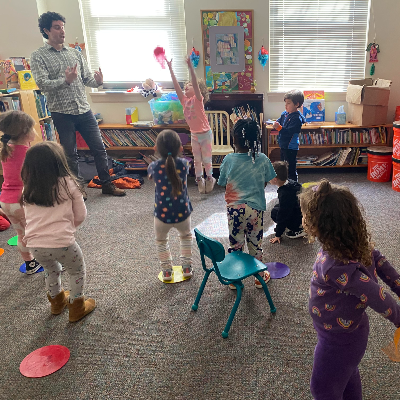 Photograph of school age children playing as a group with a music instructor.