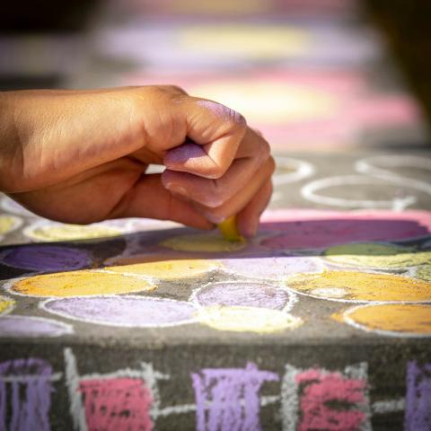 A hand drawing with chalk on the ground. There are multicolored drawings all around