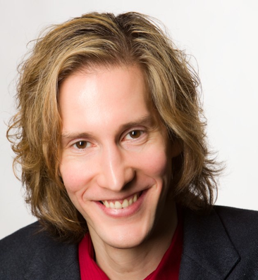 Portrait of Keir White, a smiling white man with shaggy blond hair.