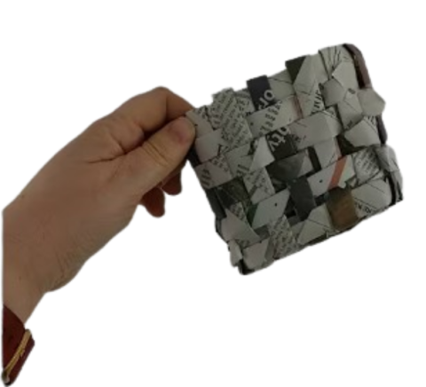 a hand holding up a basket made of newspaper