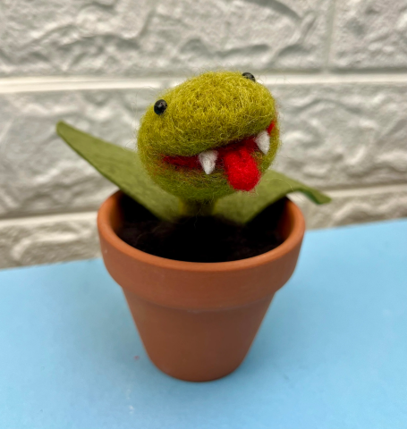 A felted carnivorous plant with fangs and tongue, in a small pot