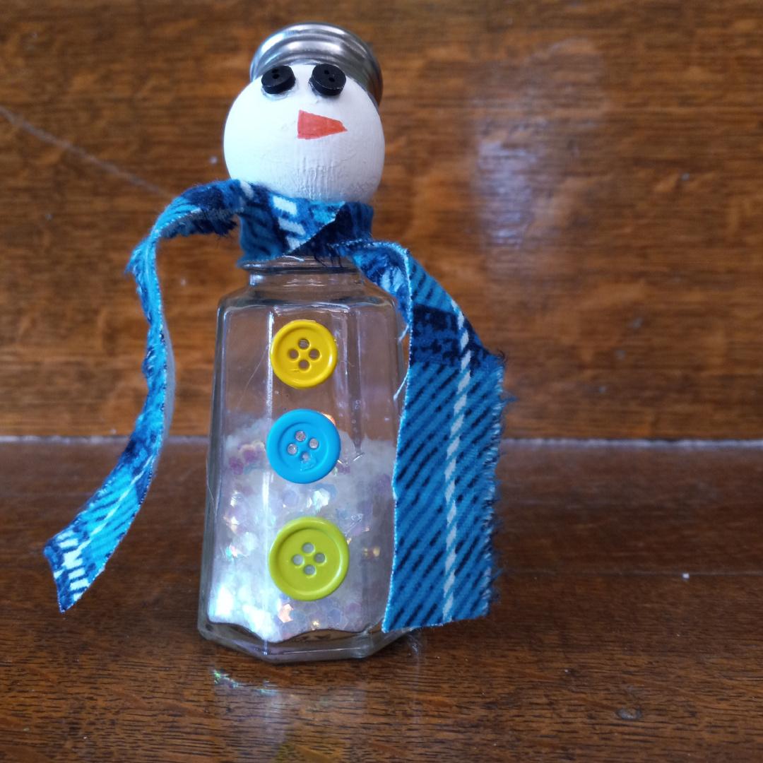 Salt shaker craft with ribbon, buttons, and a snowman's head.