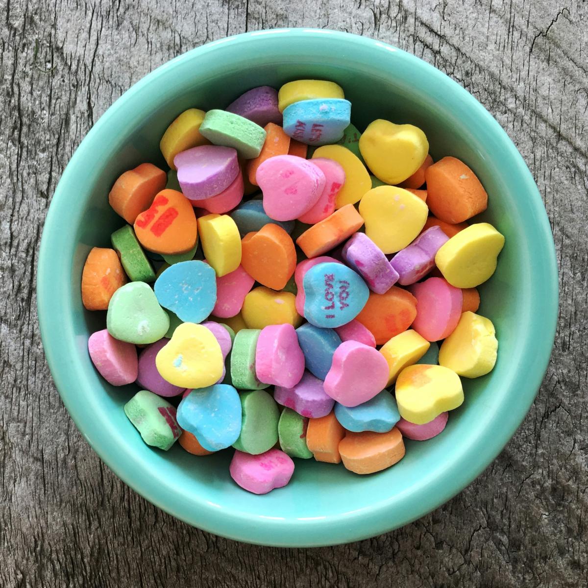 A blue bowl filled with brightly colored conversation hearts