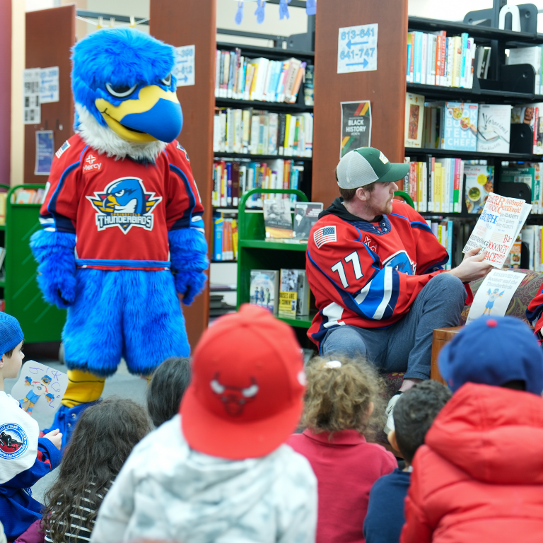 The T-birds mascot Boomer and player Drew Callin (#77) host a storytime for kids at the Sixteen Acres branch in 2023