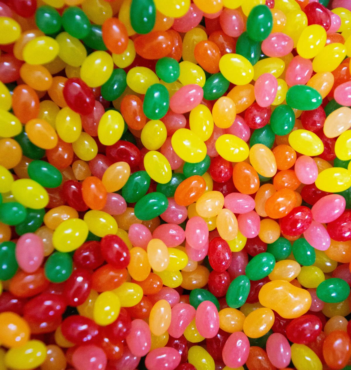 Close-up of many jellybeans in yellow, green, pink, and red.