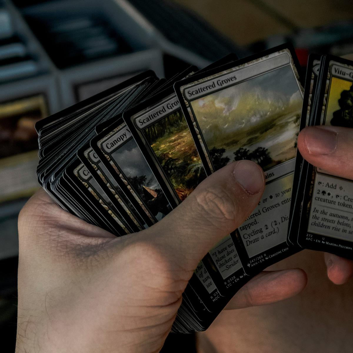 A spread of Magic the Gathering cards in a person's hands.