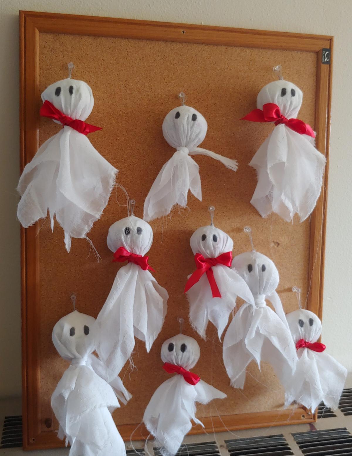 Tissue paper ghosts with red bow ties hanging from a bulletin board